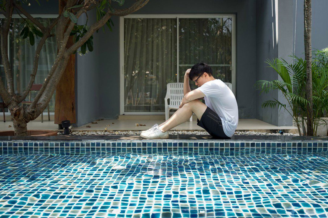 Man beside his pool worrying about high energy bills.